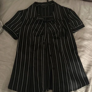 Vintage kortärmad skjorta - Svart skjorta med vita vertikala ränder och klassisk krage. Framhäver midjan och lite figursydd. Aldrig använd. Vintage 2000s. 