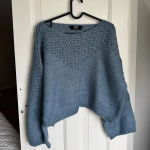 Blå stickad tröja  - Mysig blå stickad tröja från Bik Bok i ullblandning. Tröjan har ett snyggt strukturmönster upptill och på ärmarna, samt en lite lösare passform med långa ärmar och ribbade muddar. Perfekt för kyliga dagar.aldrig använd 