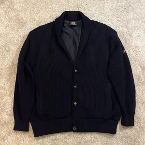 Cardigan - Hej! Säljer denna marinblå ullstickade cardiganen från märket Clipper. Håller värmen väldigt bra då den är extra fodrad inuti. Cardiganen har knappar och en knapp uppe vid kragen. Innerficka finns och materialet är 100% ren ull och inuti är 100% bomull. Storlek: medium. Skriv vid frågor/funderingar. Mvh DC 🔹