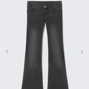 Bootcut svarta jeans med låg midja - Snygga svarta bootcut jeans med låg midja och klassisk femficksdesign. Jeansen har en lätt tvättad look och guldiga knappar framtill. Perfekt för dig som gillar retrovibbar och vill ha ett par jeans med lite extra attityd.Lappen baktill är bortklippt 