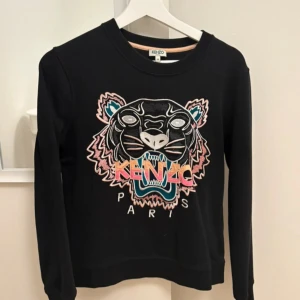 Svart Kenzo sweatshirt med tigertryck - Svart sweatshirt från Kenzo med ikoniskt broderat tigerhuvud och färgglad logga på bröstet. Använder inte 