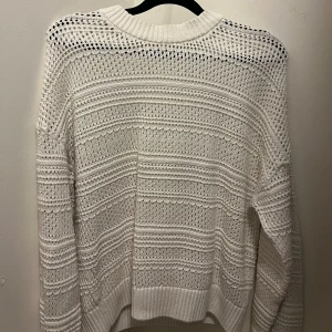 Vit stickad tröja med hålmönster - Säljer en vit stickad tröja med snyggt hålmönster och ribbade muddar. 