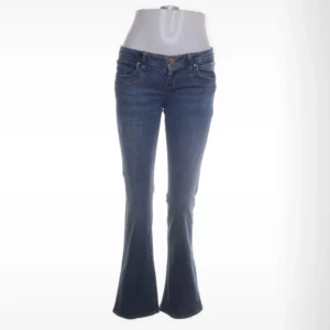 Blå bootcut jeans från Ltb - Snygga blå jeans från Ltb med bootcut passform och klassisk femficksdesign. Jeansen har låg midja och är tillverkade i slitstarkt denim med tydliga sömmar och Ltb-lapp bak i linningen. Perfekta för dig som gillar retrovibbar och bekväm stil.Storlek 26/32