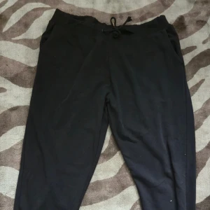 Svarta mjukisbyxor med snörning - Svarta mjukisbyxor med dragsko i midjan och bekväm passform. Byxorna har fickor på sidorna, tillverkade i bomulll. Använda väl och är sliten i midjebandet (se sista bild) men inget som har påverkat bandets användning