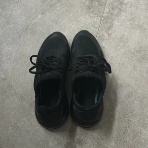 Nike Air Max 270 helsvarta sneakers - Säljer ett par helsvarta Nike Air Max 270 sneakers med klassisk luftig mesh och syntetmaterial, samt den ikoniska Air Max-sulan för extra komfort. Snygg, sportig design med snörning och diskret Nike-logga på sidan. Perfekta för dig som gillar stilrena och bekväma skor.