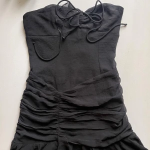 Svart klänning Zara  - Supersnygg svart kort klänning med snörning i halsen och volangkant nertill. Från Zara 