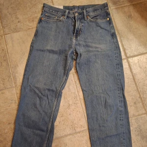 Blå relaxed fit jeans från H&M - Säljer ett par klassiska blå jeans från H&M i relaxed fit. Jeansen har raka ben, fem fickor och normal midja. Tillverkade i bomull med snygg tvättad look och kontrastsömmar. Perfekta för en chill och avslappnad stil.