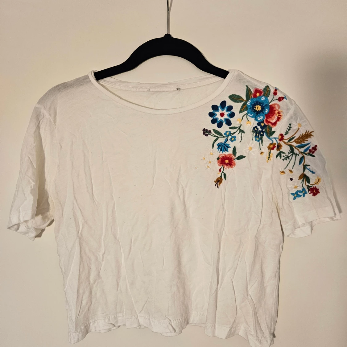 Vit topp med broderade blommor