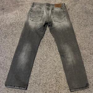 Grå slitna jeans i slimfit - Säljer ett par grå jeans med slitningar och snyggt tvättad look. Modellen är slimfit, enkel att matcha med.