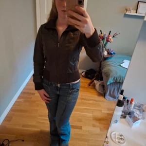 Brun skinnjacka från Vero Moda - Säljer en brun skinnjacka från Vero Moda i modell Belleville Short Leather. Jackan har dragkedja framtill, ribbade muddar vid ärmslut, krage och midja samt två fickor med dragkedja. Perfekt för dig som vill ha en klassisk och snygg look.