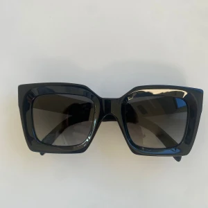 Svarta solglasögon från Celine - Snygga svarta solglasögon från Celine med breda, fyrkantiga bågar och mörka linser. Glasögonen har en cool, chunky design och Celine-logga i guld på sidan. Kommer med originalfodral,  ask och kvitto från Celinebutiken i Barcelona. 