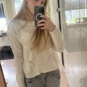 Beige stickad tröja från Jacqueline de Yong - Säljer en beige stickad tröja från Jacqueline de Yong i storlek S. Tröjan har ett snyggt hålmönster med vågiga detaljer och rund hals. Modellen är lite loose och har långa ärmar. Tyget är väldigt lent och skönt mot huden.