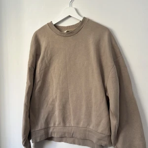 Beige sweatshirt från Gina Tricot L - En beige sweatshirt från Gina Tricot i oversized modell. Tröjan har rund halsringning, ribbade muddar vid ärmslut och nederkant samt är tillverkad i mjuk bomull. Perfekt för en chill och avslappnad stil.