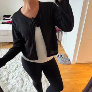 Svart kofta med knyt - Svart, tunn och mjuk kofta med lång ärm och knyt framtill vid halsen. Använd fåtal gånger - mycket bra skick!