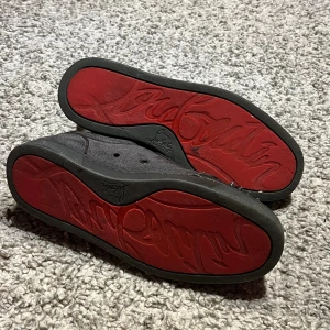 Christian Louboutin gråa sneakers med nitar - Grå sneakers från Christian Louboutin i mocka med ikoniska röda sulor. Billigare vid snabb affär