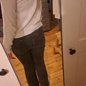 Gråa/svarta bootcut jeans från Kappahl - Snygga svarta jeans från Kappahl i storlek 152. Modellen har bootcut-ben och klassisk femficksdesign. Jeansen är i stretchigt denimtyg och har normal passform med knapp och dragkedja framtill.