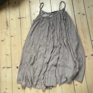 Beige sommarklänning från KappAhl - Luftig beige klänning från KappAhl med tunna axelband och flätad detalj upptill. Klänningen har en avslappnad passform och är tillverkad i ett lätt material som passar perfekt för varma dagar.