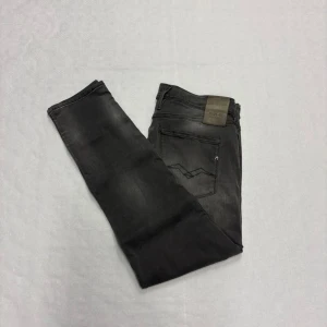 Replay Anbass Hyperflex  - Snygga Replay Hyperflex jeans i tvättad grå färg med klassisk femficksdesign och raka ben. Jeansen har diskreta slitningar och logga på bakfickan samt läderpatch i midjan. Stretchigt material för extra komfort och stilren look.