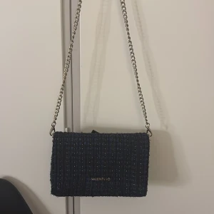 Mörkblå axelväska från Valentino - Snygg mörkblå axelväska från Valentino med kedjerem i silver färg. Väskan har en rektangulär form och är tillverkad i ett grovt, vävt tyg. Köpt för 1300kr säljer för 500❤️