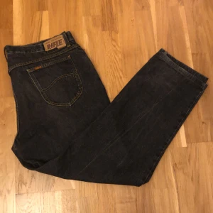 Mörkblå jeans från Rifle - Säljer ett par mörkblå jeans från Rifle med klassisk femficksdesign och kontrastsömmar. W 42 L 36 Jeansen har rak passform och normal midja, tillverkade i robust denim. 