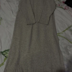 Beige stickad långärmad klänning - Mysig beige stickad klänning med lång ärm och ribbade muddar vid ärmslut och nederkant. Rak och enkel modell som är perfekt för kyligare dagar. Klänningen har en mjuk känsla och passar dig som gillar en avslappnad och stilren look.