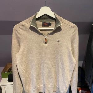 Morris tröja beige merinoullströja  - Snygg beige tröja från Morris i 100% merinoull. Tröjan har half zip med läderdetalj, hög krage och logga på bröstet. Perfekt för lager-på-lager och passar till nästan allt. Långärmad och mjuk känsla. Storleken är L i barnstorlek så ungefär XXS/XS. Passar dig som är 170. Den har en grön innerkrage och Morris märket är broderat i samma grön. Hör av dig vid frågor😁
