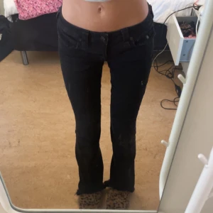 Svarta True Religion Joey flare jeans - Säljer ett par svarta True Religion Joey jeans med låg midja och flare-ben. Jeansen har råa kanter och klassiska detaljer med fickor och logga bak. Snygg passform och cool look. Storlek 27/S ❤️