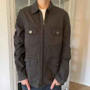  Mörkgrå overshirt från Oscar Jacobson - S - Jag säljer den här riktigt snygga overshirten från Oscar Jacobson. Den är använd men fortfarande i bra skick utan skador. Den är i storlek S och modellen heter Raf Shirt Jacket. Tveka inte att höra av er!