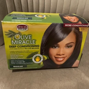 African Pride Olive Miracle Deep Conditioning Kit - Säljer en Olive Miracle Deep Conditioning kit från African Pride. Innehåller no-lye relaxer, schampo och aloe vera conditioner. Berikad med afrikansk sheasmör, olivolja, aloe och ricinolja. Förpackningen är grön och gul med tydliga produktbilder och instruktioner.
