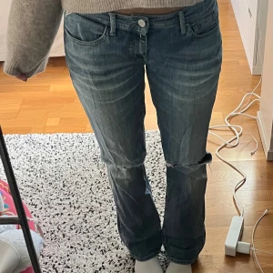 Replay blå jeans bootcut - Ett par ljusblå jeans från Replay i bootcut/straight modell. Jeansen har slitningar/två hål vid knäna och är lite ljust tvättade. Supercoola!! Har använt mycket men fortfarande i fint skick. Midjemått 42 cm innerbenslängd 78 cm