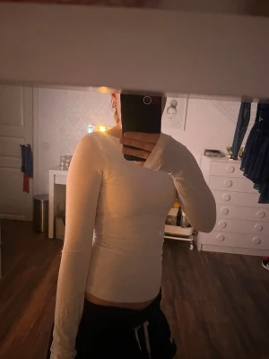 Vit långärmad topp med öppen rygg - Säljer en vit långärmad topp med tight passform och öppen rygg. Toppen är enkel och stilren framtill, men har en snygg djup urringning i ryggen som ger en cool twist. Aldrig använd men lappar borttagna.