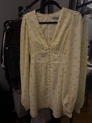 Blommig ljusgul kortklänning från Adoore - Säljer min superfina gula klänning från Adoore! Använd endast en gång och i mycket fint skick. Fantastisk passform och perfekt för både fest och sommarens tillfällen. Hör av dig vid intresse!