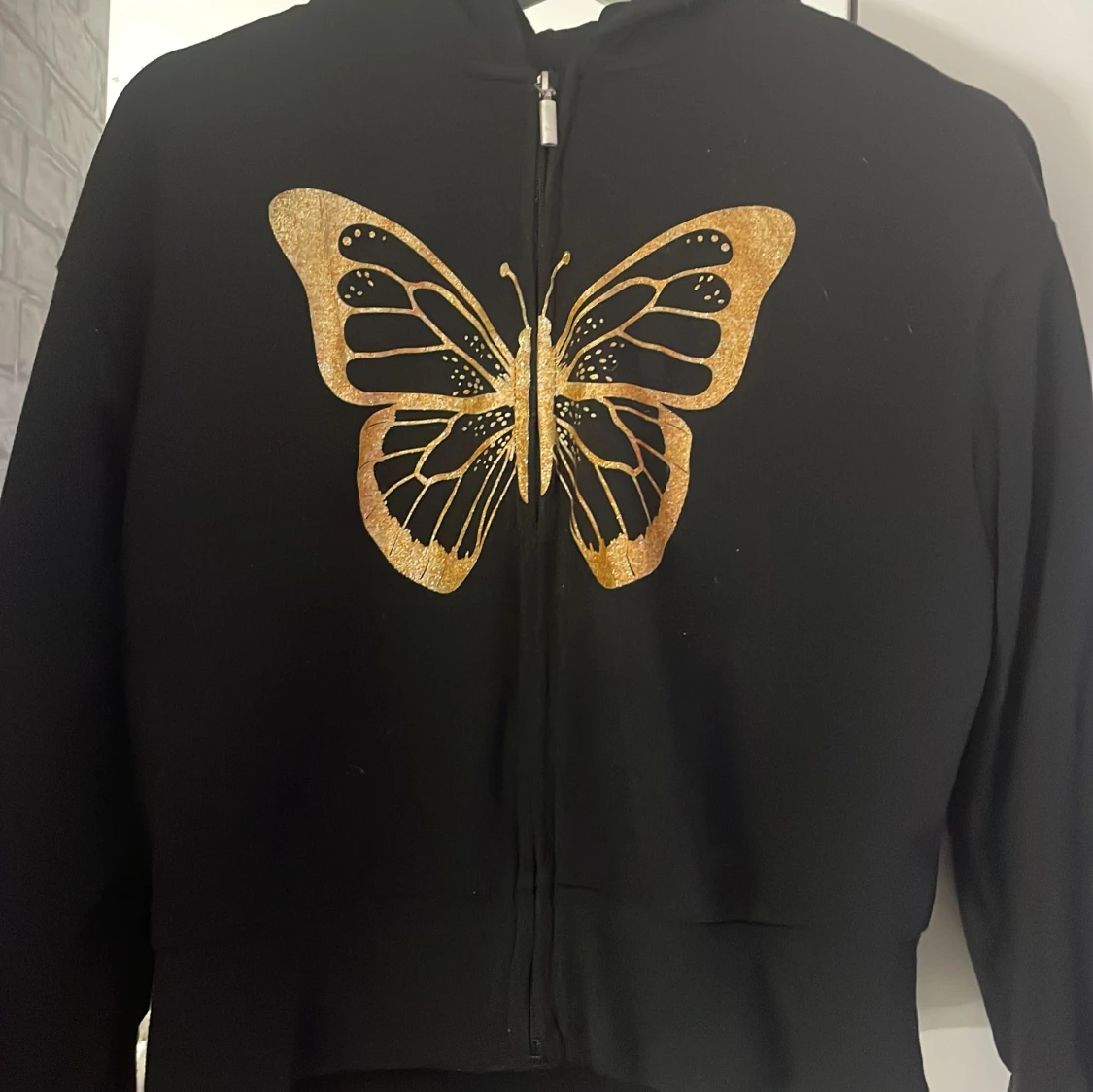 Svart hoodie med guldglittrig fjäril