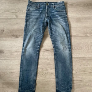Blå skinny jeans från Jack & Jones - Snygga blå jeans från Jack & Jones i modellen skinny med klassisk femficksdesign och slitna detaljer. Jeansen har normal passform i midjan och är tillverkade i jeansmaterial med coola tvättade effekter på benen. Passar för dog som är lite över 180. Skriv för mer bilder med mera