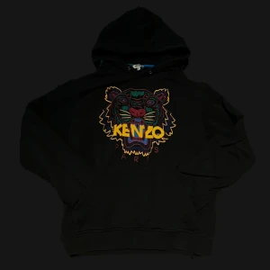 Svart Kenzo hoodie med tigerbrodyr - Svart hoodie från Kenzo med ikonisk tigerbrodyr i flera färger och Kenzo-logga framtill. Tröjan har huva, känguruficka och är tillverkad i 100% bomull. 