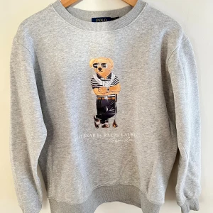Grå sweatshirt Polo Bear Ralph Lauren - Säljer en grå sweatshirt från Polo Ralph Lauren med  Polo Bear tryck. Tröjan är storlek M men passar även S den är i bra skick.