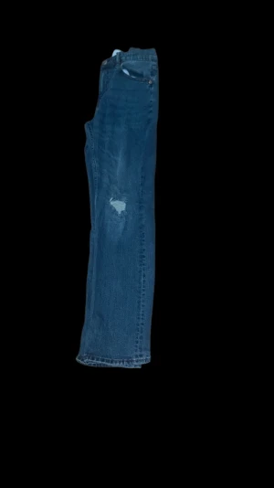 Lager 157 blå jeans med slitningar - Blå Levi's 517 jeans med klassisk femficksdesign och slitningar på båda knäna. Jeansen har rak passform och är tillverkade i robust denim. Perfekta för dig som gillar en avslappnad och tidlös look.