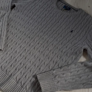 Grå kabelstickad tröja Polo Ralph Lauren - Tjena, säljer min mycket sparsamt använda kabelstickade tröja från ralph lauren. Tröjan sitter som ett mellanting mellan L och M. Pris kan diskuteras. Tveka inte att ställa några frågor eller skicka in pris förslag💯🔥 Snygg grå kabelstickad tröja från Polo Ralph Lauren med klassisk rund hals och broderad logga på bröstet. Tröjan har långa ärmar och ribbade muddar vid ärmslut och nederkant. Perfekt för dig som gillar stilren och tidlös design.