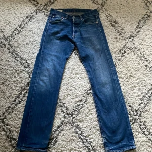 Levi's 501 jeans blå 29/32 - Klassiska Levi's 501 jeans i blå denim med raka ben och fem fickor. Modellen har knappgylf och normal passform. Levi's Premium-märke på insidan och läderpatch bak i midjan. Perfekt för dig som gillar tidlös stil och äkta denim. W29 L32  säljer då jag växt ur de. PRIS KAN DISKUTERAS. 