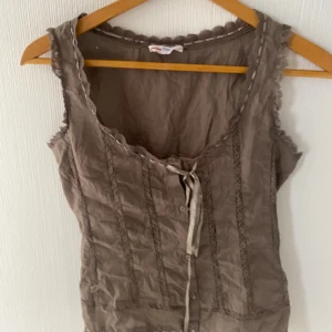 Brun topp - Brun snygg vintage topp med spetsdetaljer och justerbar i midjan!