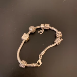 pandora armband  - Unikt armband i silverfärg med flera berlocker. Armbandet har detaljerade ringar och lås i metall, perfekt för dig som gillar personliga smycken.