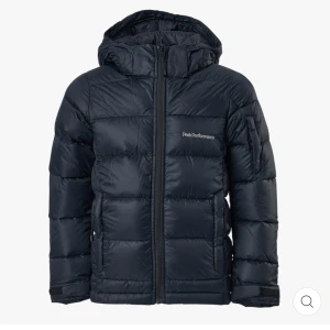Mörkblå dunjacka Peak Performance- Frost Down jacket - Säljer en mörkblå dunjacka från Peak Performance med huva och dragkedja framtill. Den funkar perfekt för kalla dagar då den är en varm dunjacka. 