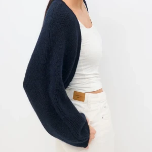 Mörkblå stickad bolero från Gina Tricot - Säljer en mörkblå stickad bolero från Gina Tricot. Den har långärmade, loose passform och är perfekt att slänga över en topp. Materialet är mjukt och stickat. Helt oanvänd, endast testad. Köptes för 300kr säljer för 200kr!