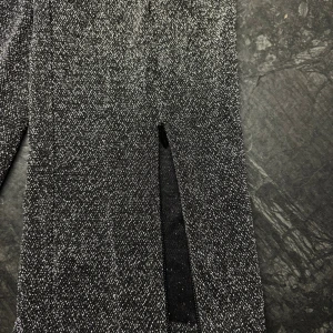 Glittriga svarta byxor/leggings från Gina Tricot - Snygga svarta byxor/leggings från Gina Tricot med glittrig finish. Byxorna har rak passform, resår i midjan och är tillverkade i ett stretchigt material med metallictråd för extra shimmer samt dragkedja nertill. Perfekta för dig som vill sticka ut med en cool look.