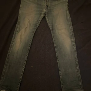 Jacob Cohën ljusblå jeans - Snygga ljusblå jeans från Jacob Cohën med klassisk femficksdesign och diskret slitning på benen. Jeansen har normal passform och raka ben, tillverkade i mjukt denimtyg med detaljer i kontrastfärg vid sömmar och knapp. Det finns en lagning vid skrevet men den märkes knappast.