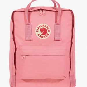 Rosa Kånken ryggsäck från Fjällräven - Rosa Kånken ryggsäck från Fjällräven med klassisk fyrkantig form, dubbla handtag upptill och justerbara axelremmar. Väskan har ett stort huvudfack, framficka med dragkedja och sidofickor samt sittunderlag. Säljer då den inte kommer till användning🤩.
