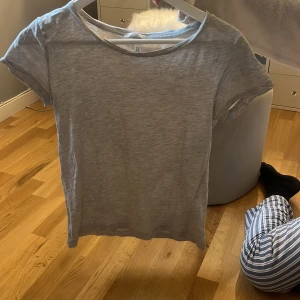 Ljusgrå basic t-shirt från H&M XS - Enkel och stilren ljusgrå t-shirt från H&M i storlek XS. T-shirten har rund halsringning och korta ärmar. Tillverkad i mjuk bomull, perfekt för en clean och avslappnad look.