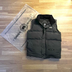 Grå canada goose väst black label - Hej säljer en ny canada goose väst som är skön och fräsch. Bilderna kan vara lite mörka så skriv gärna om ni vill ha fler bilder eller om ni har funderingar👍