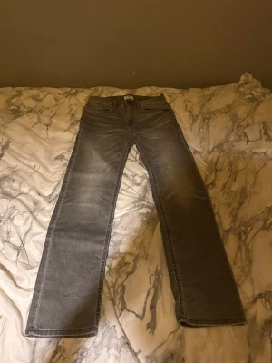 Grå jeans straight fit - Säljer ett par gråa jeans med straight fit. Klassisk femficksmodell och normal passform. Jeansen har en snygg tvättad look och är tillverkade i slitstarkt denim. Perfekt för dig som gillar stilrena och tidlösa jeans.
