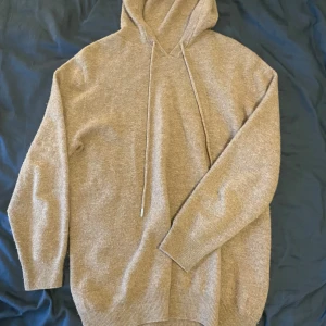 Beige hoodie i kashmirblandning - Mysig beige hoodie i kashmirblandning med långa ärmar och ribbade muddar. Tröjan har huva med snörning och en avslappnad passform, perfekt för chill dagar. Enkel och stilren design som funkar till det mesta😆